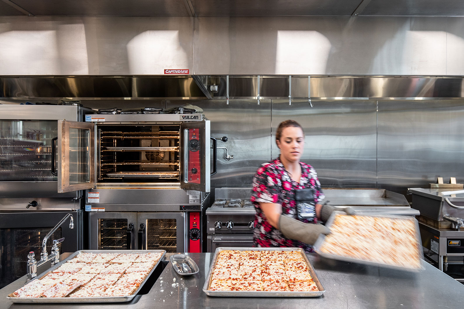 Clear Lake High School Food Services photo of woman preparing pizza lunch for students 