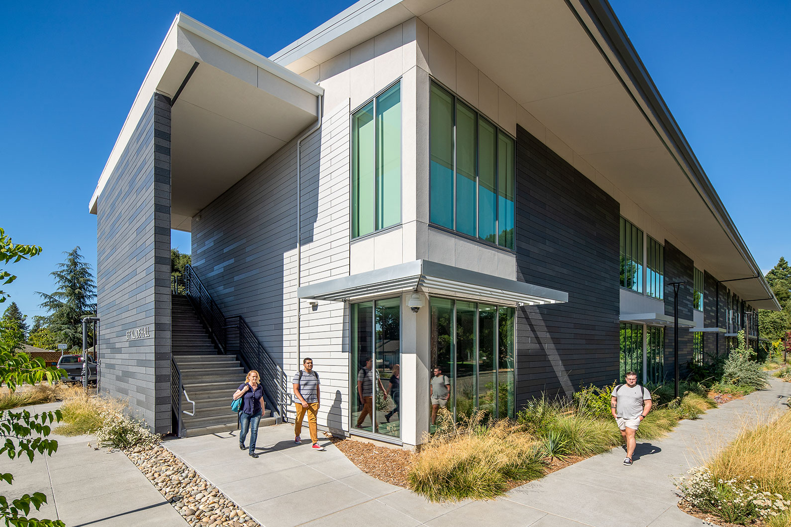 Exterior corner view of building with 3 students walking