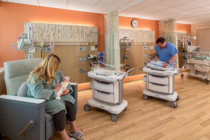 Nurse with baby and mother with baby in Neonatal Intensive Care Unit