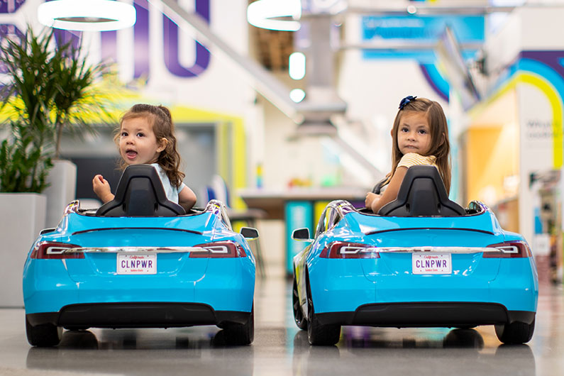 Two girls playing in electric car display