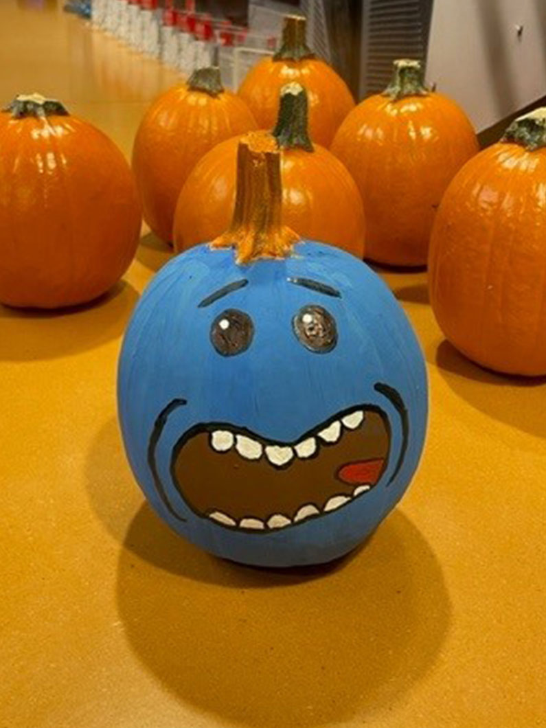 Blue painted pumpkin with face and orange pumpkins in background