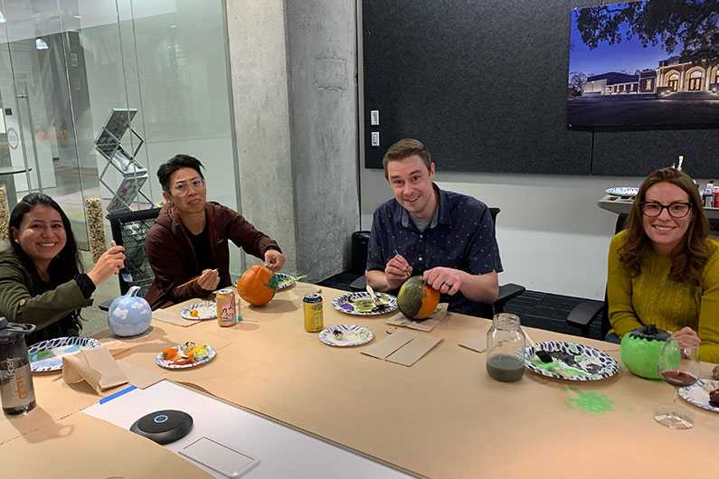 4 people painting pumpkins at TLCD office party