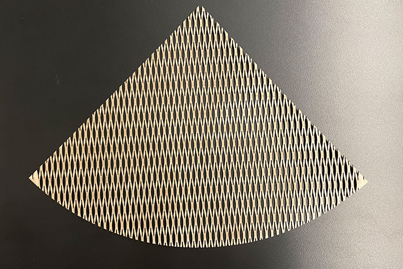 Laser cut plywood in the shape of a cone on black surface