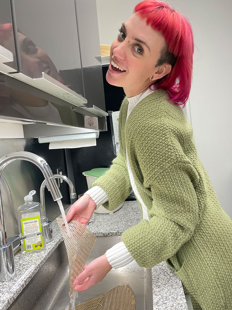 Smiling woman running water over plywood form at sink