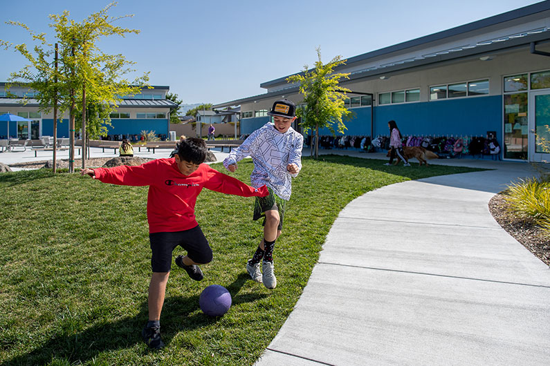 Two boys kicking soccer ball outside at Loma Vista Immersion Academy