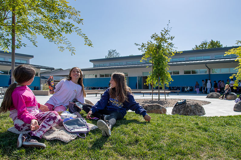 Two girls sitting on grass at Loma Vista Immersion Academy