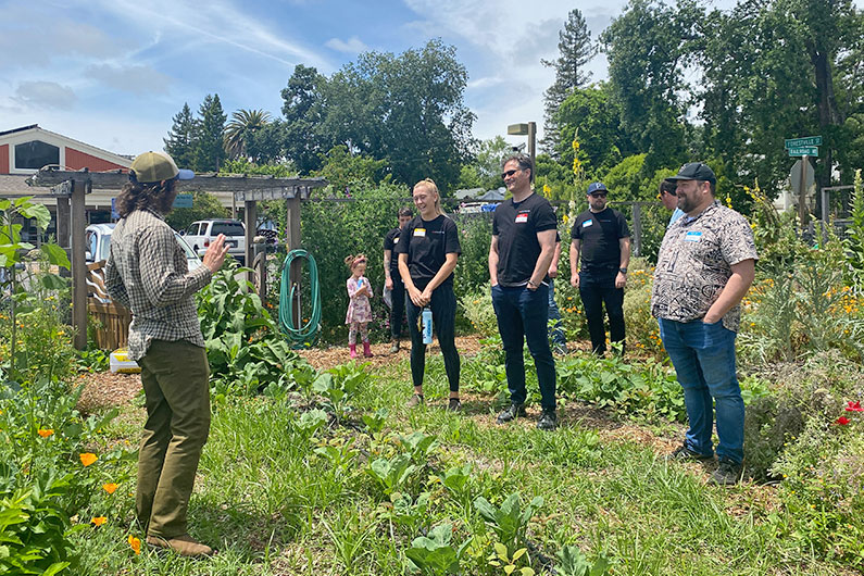 Man talking to volunteer group in garden at Food For Thought Food Bank