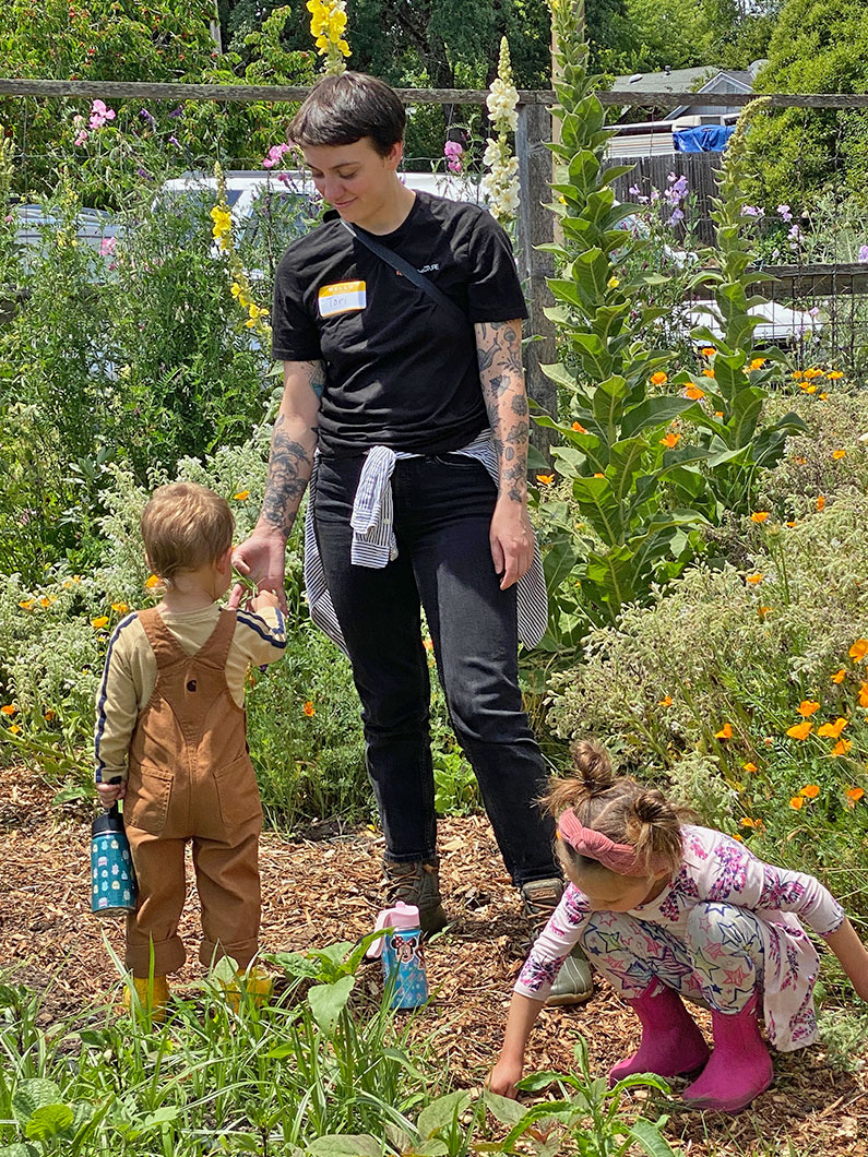 Woman with two kids picking weeds in garden