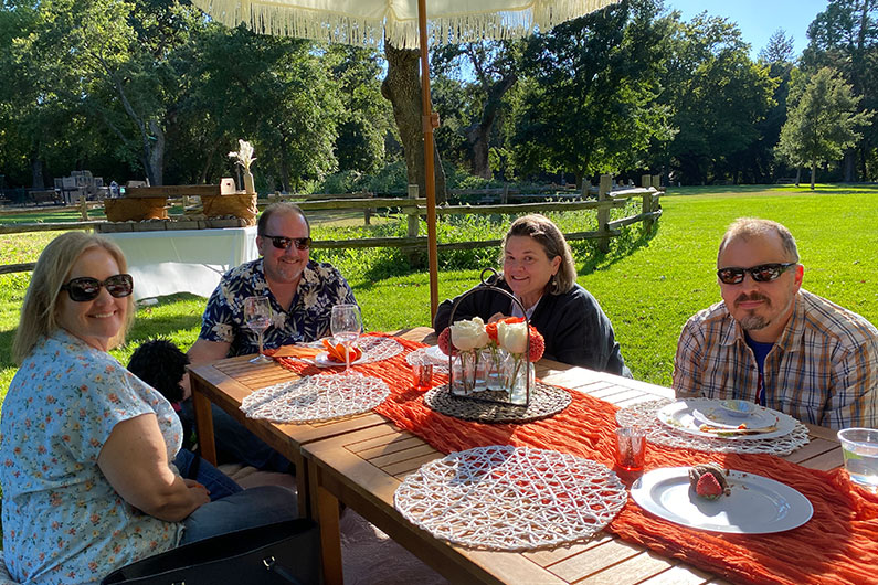 TLCD team relaxing under umbrella at summer picnic