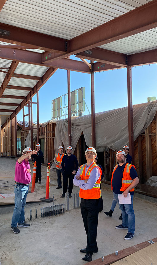 TLCD team in hard hats and vests touring elementary school job site