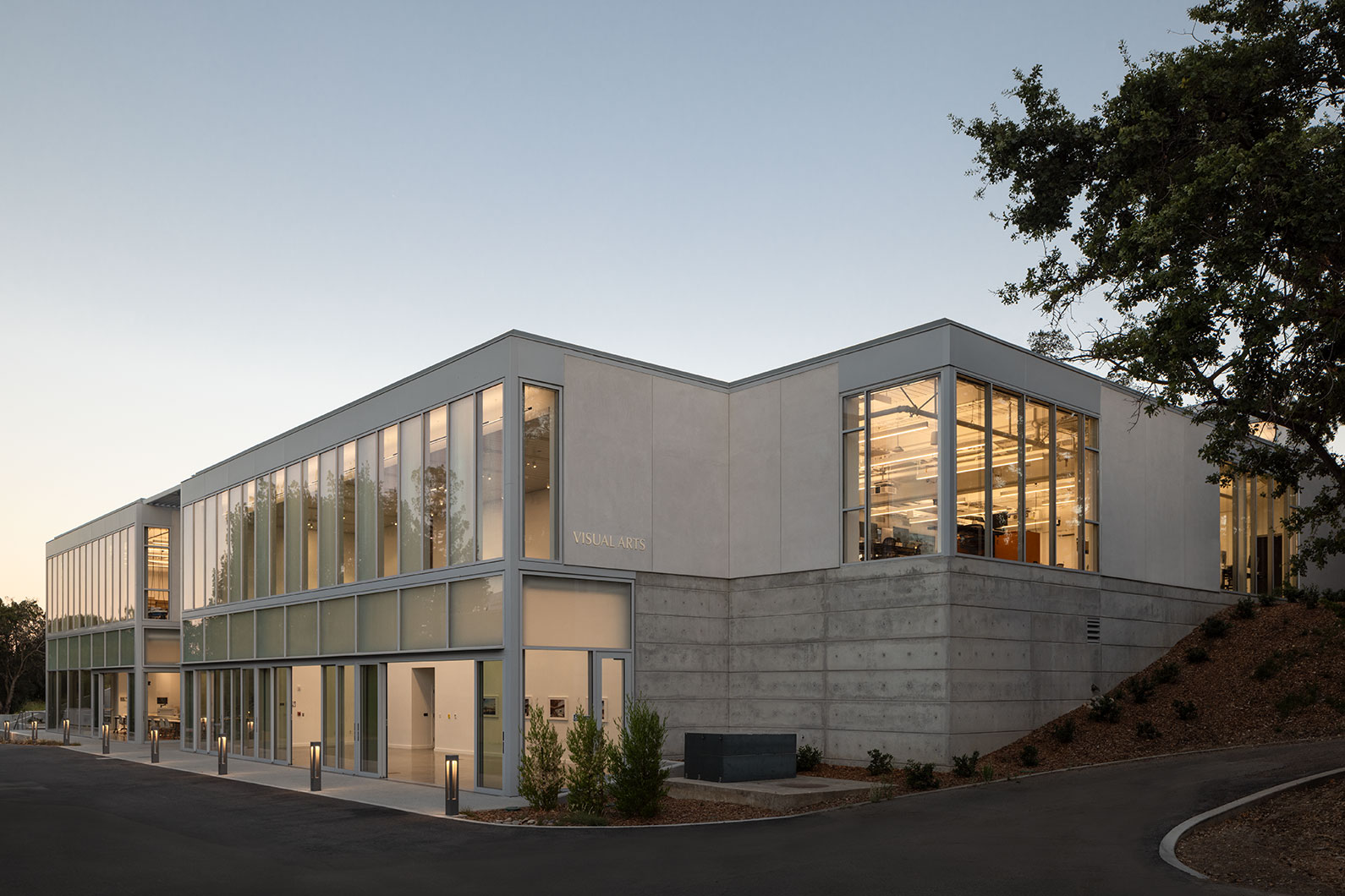 Dusk shot of front of the Visual Arts Building showing lights on inside classrooms