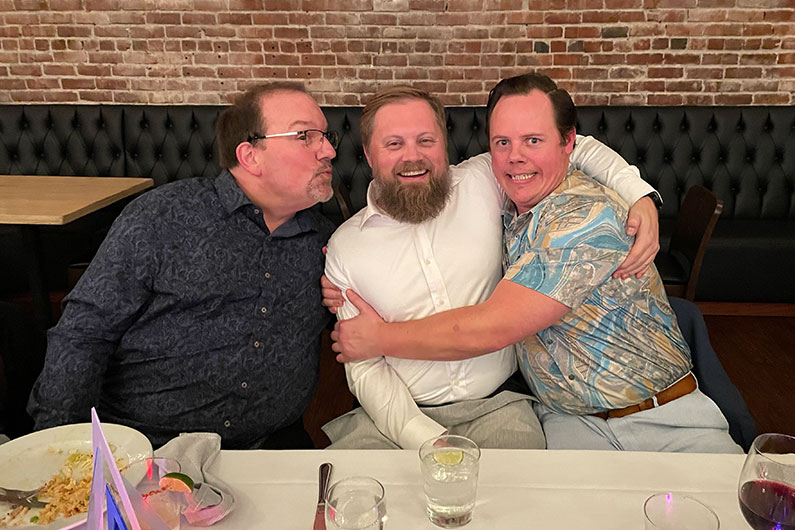 3 men sitting a table and "mugging" for the camera