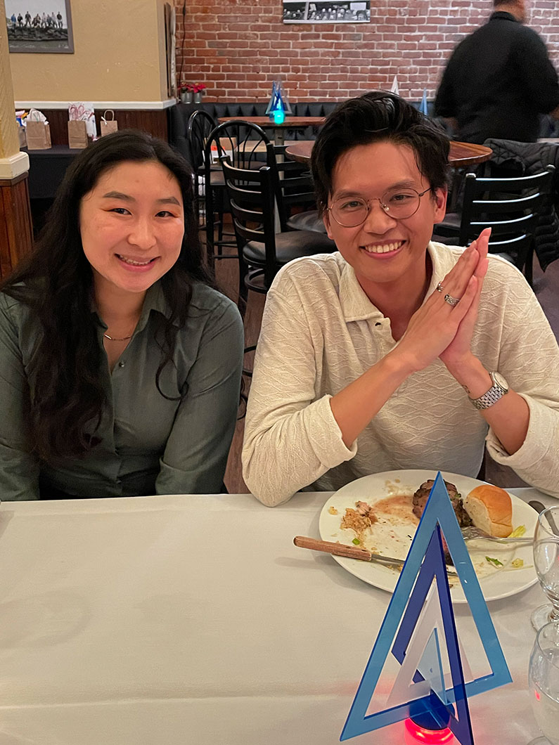 Man and woman smiling while seated at table for TLCD holiday party