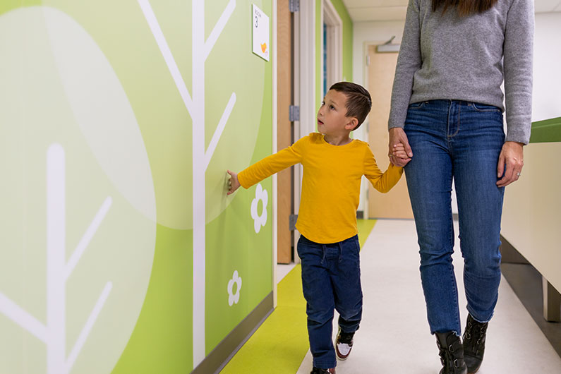 Close up detail of boy holding mother's hand while he looks at tree wall mural