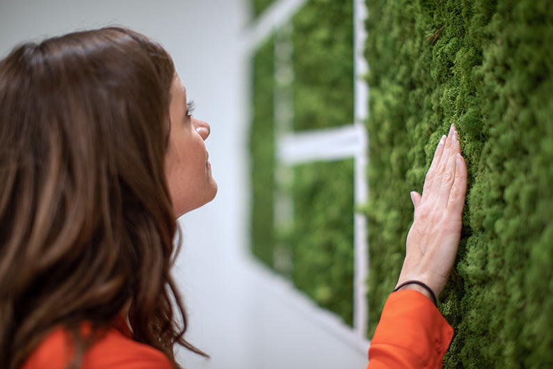Close up image of woman touching moss wall in healthcare setting