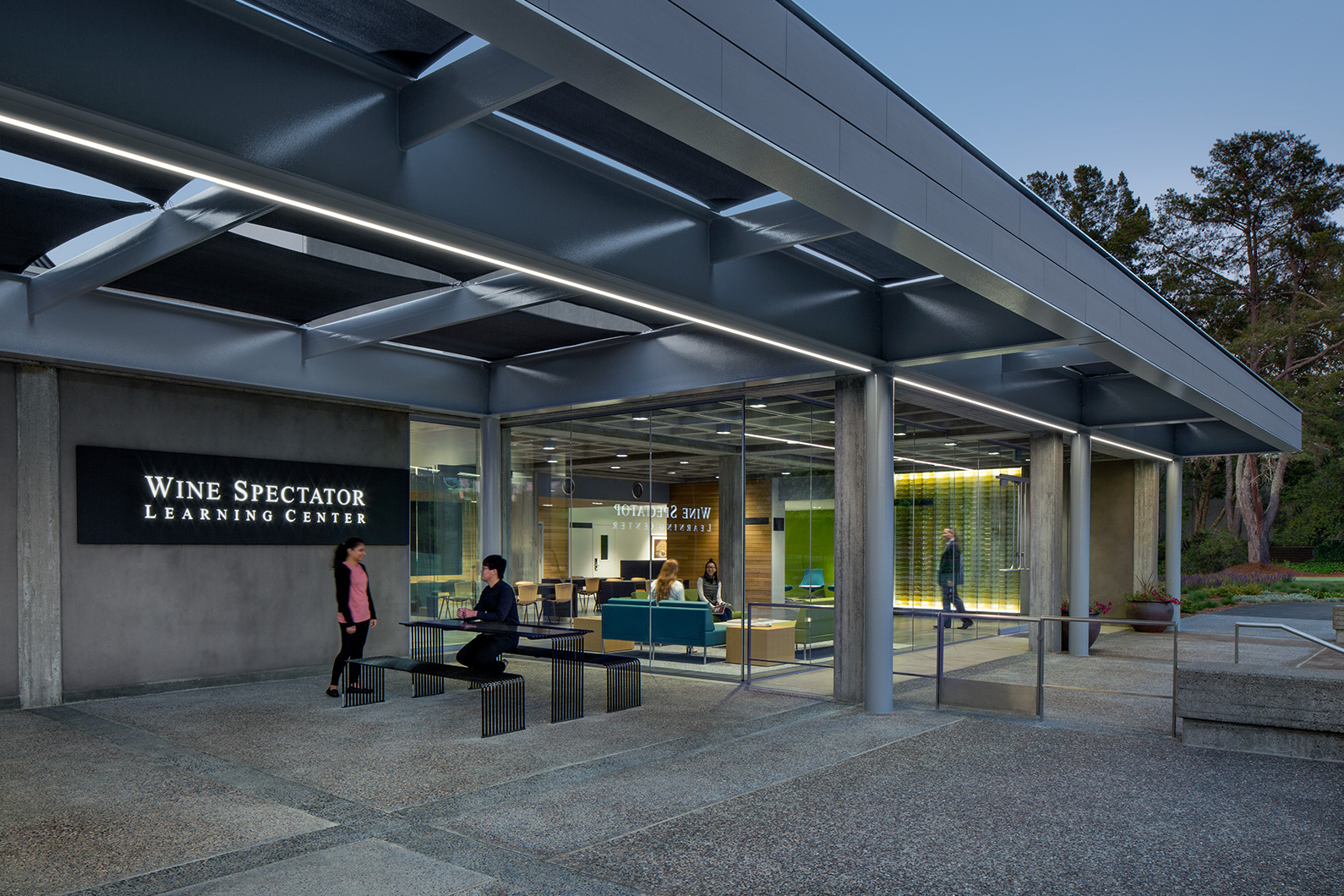 Exterior dusk photo of people gathering inside and outside at Wine Spectator Learning Center at Sonoma State University