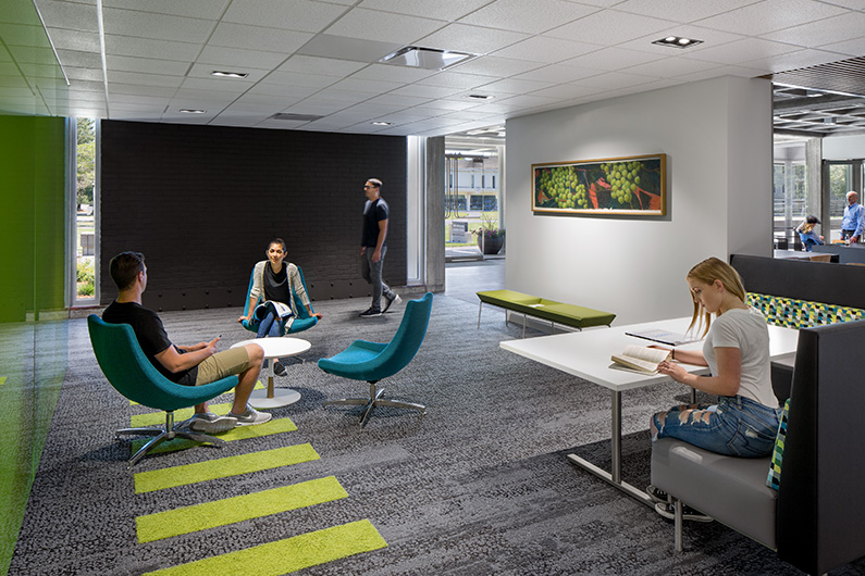 Interior photo of 4 students in small breakout space with green glass feature wall for small group gathering