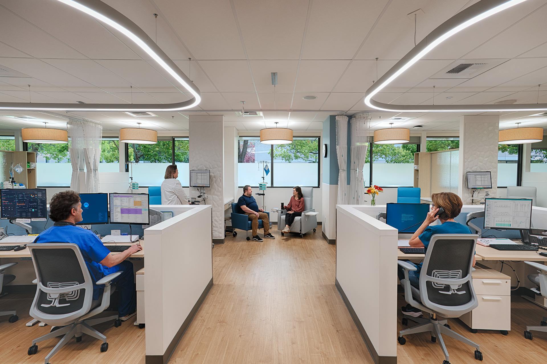 Kaiser Oncology Expansion - Two people sitting together in oncology infusion bay with a female nurse sitting to the right at desk, and male nurse sitting to the left at desk