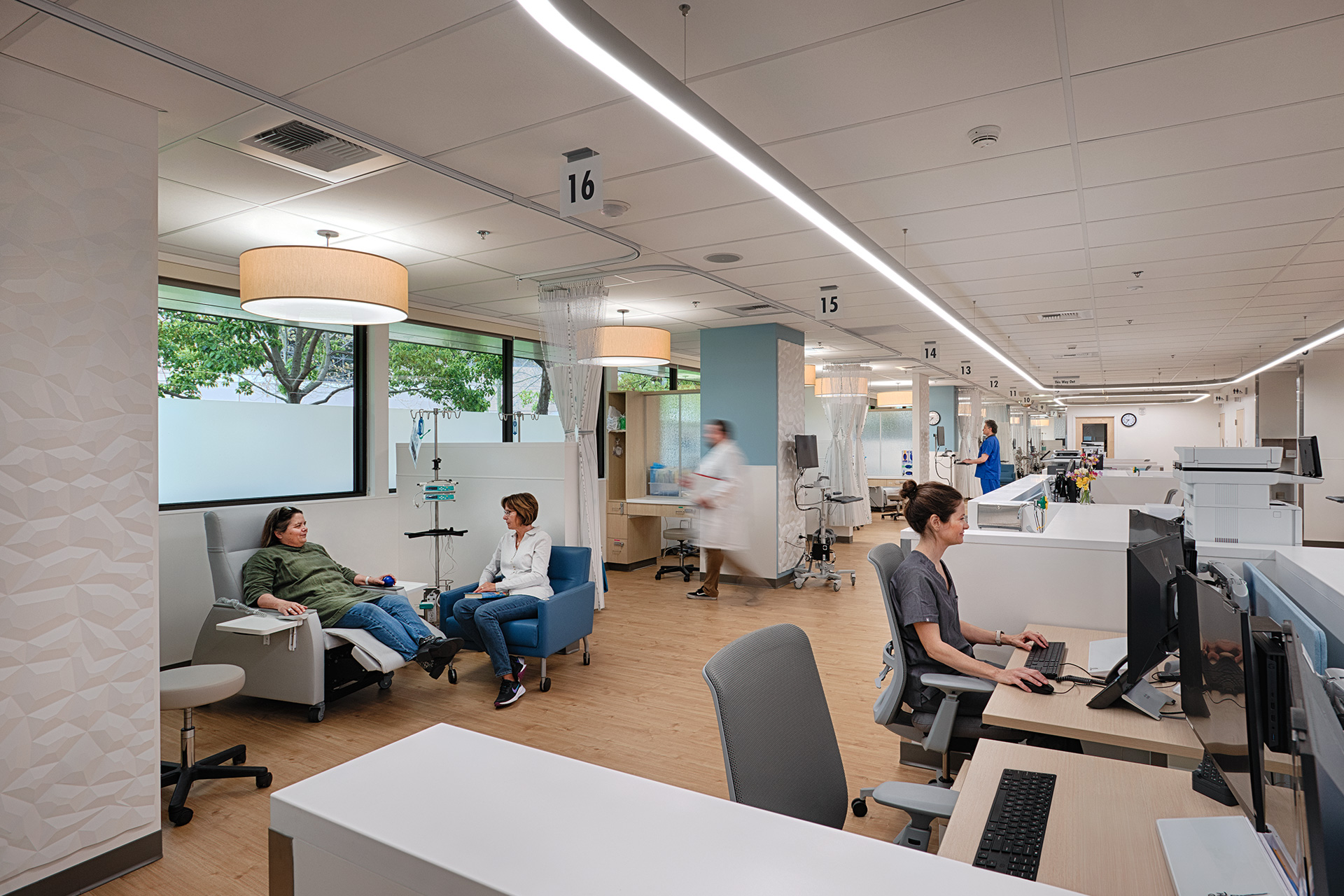 Kaiser Oncology Expansion - Interior photo of patient and family member in Oncology infusion bay, with nursing staff in the background