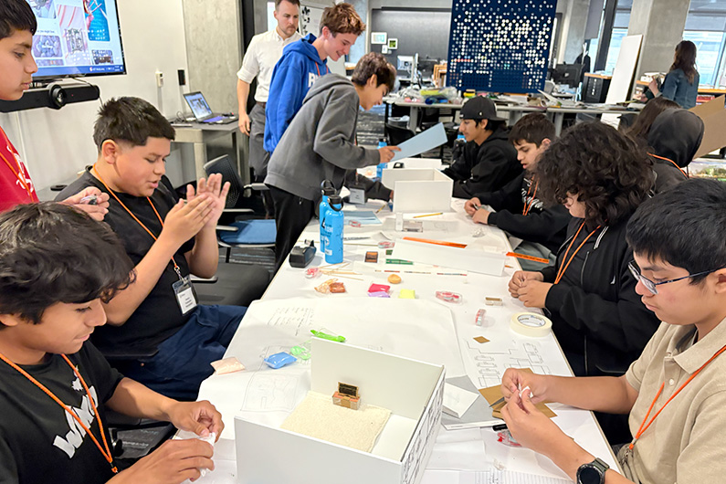 Looking down long table at students working on design project