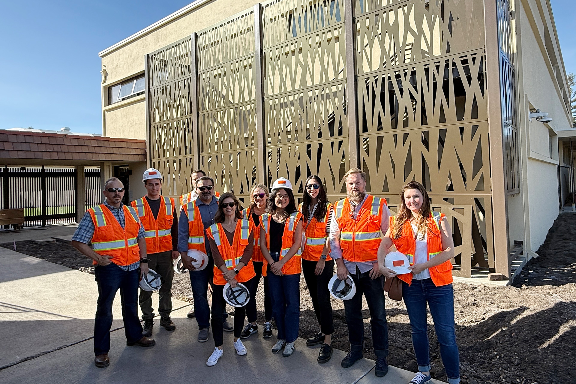Group shot of 10 TLCD staff at job site with Jessica Guo in the middle