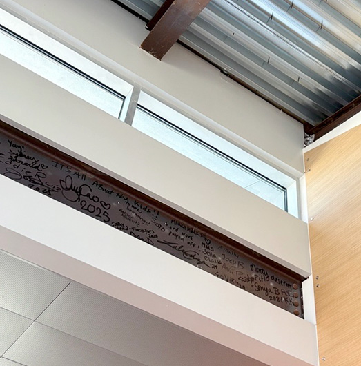 Structural beam inside Montgomery High School with signatures and messages on the metal beam