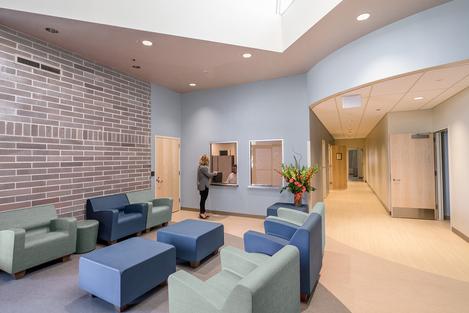 Interior photograph of woman at counter of the Sonoma County Crisis Stabilization Unit with full waiting room in foreground
