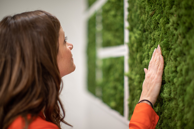 Woman touching a live moss wall at Kaiser Behavioral Health