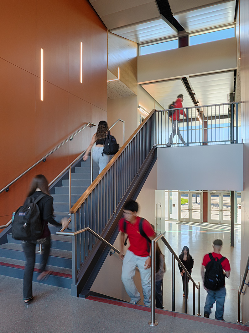 Interior photo of central staircase with students walking up and down and lots of natural daylight from windows