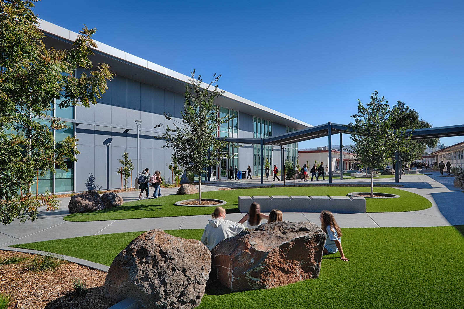 Courtyard view of new classroom building with a roof canopy connecting to the original campus