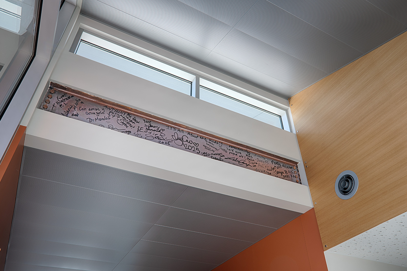 Hand-signed structural beam mounted above staircase reads "it's all about the kids"