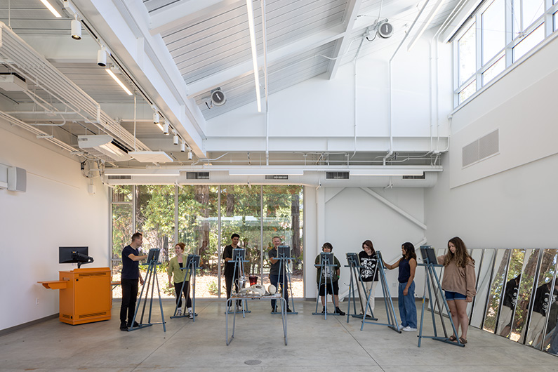 Painting studio shows students at easels with natural day light and open doors to courtyard - Design for STEM and Arts Education