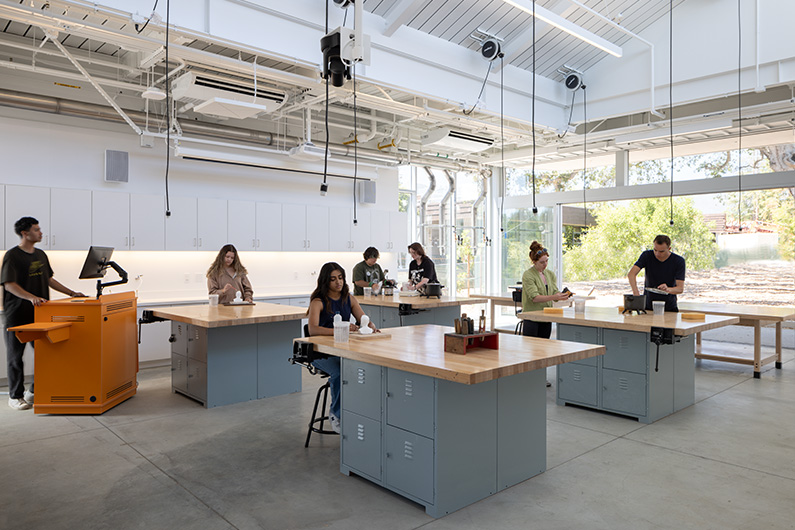 Students working in lab with power cords strung from ceiling and group work tables - Design for STEM and Arts Education